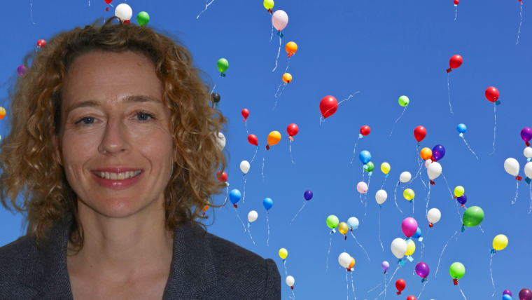 Photo of Polly Waite against a backdrop of colourful balloons floating into a blue sky